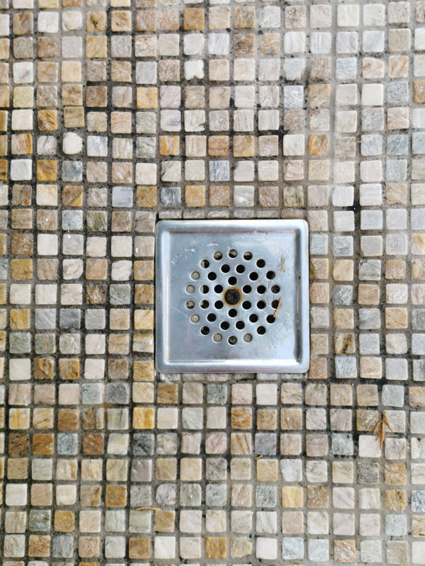 plum hole for the shower in the floor with a small mosaic