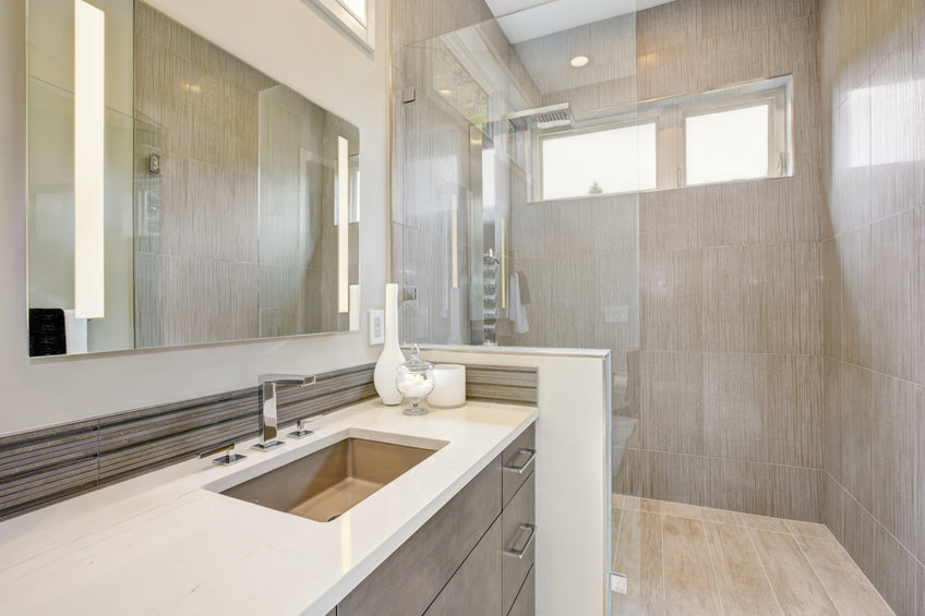 Contemporary bathroom features a dark vanity cabinet fitted with rectangular sink and walk-in shower.